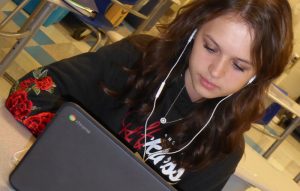 Student working at a computer desk in a dark shirt.