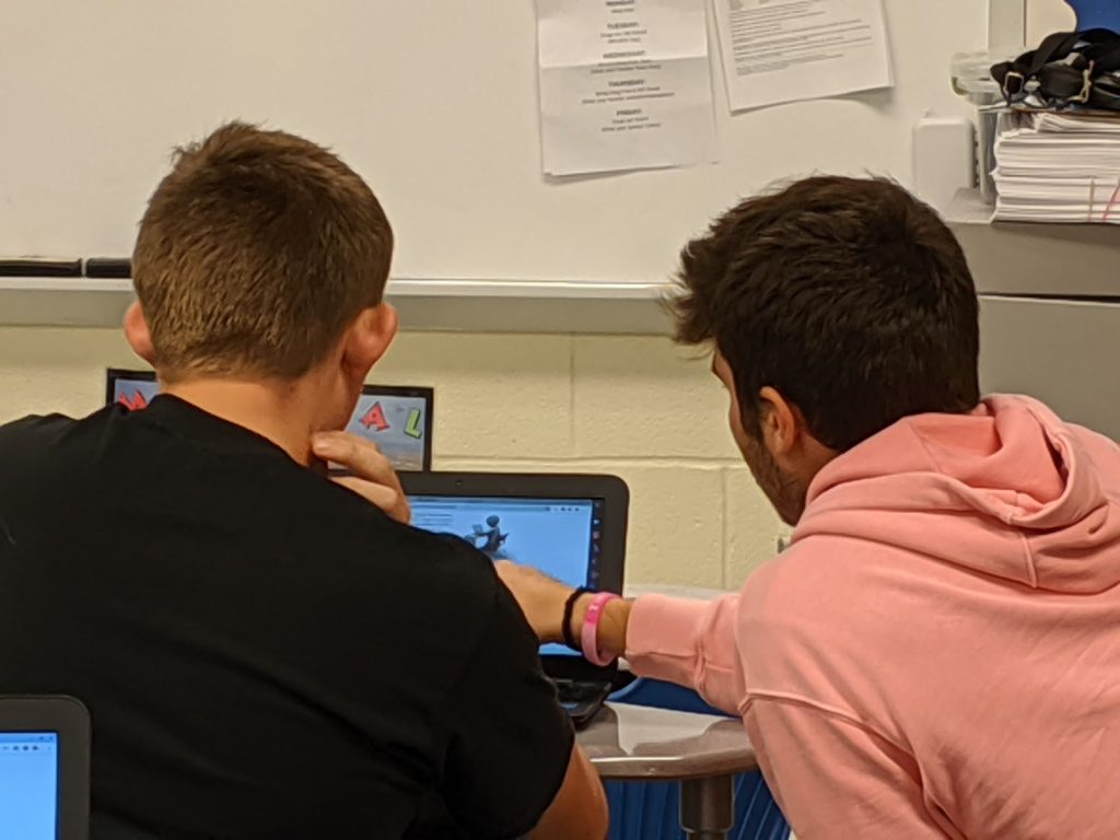 Two students looking at a computer screen, engage and collaborating on what they are looking at.